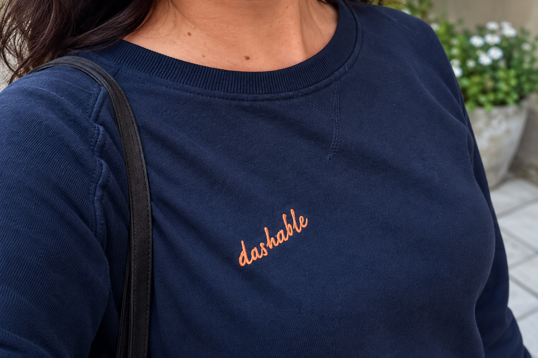 Close-up of a navy Dashable sweatshirt with an orange embroidered logo